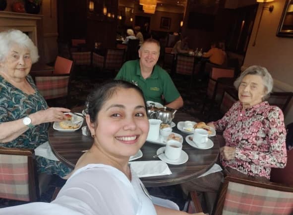 Residents enjoying afternoon tea at the Atholl Hotel, seated at a beautifully set table, smiling and sharing stories in a warm and welcoming atmosphere.