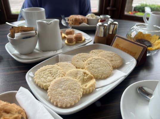 Residents enjoying afternoon tea at the Atholl Hotel, seated at a beautifully set table, smiling and sharing stories in a warm and welcoming atmosphere.